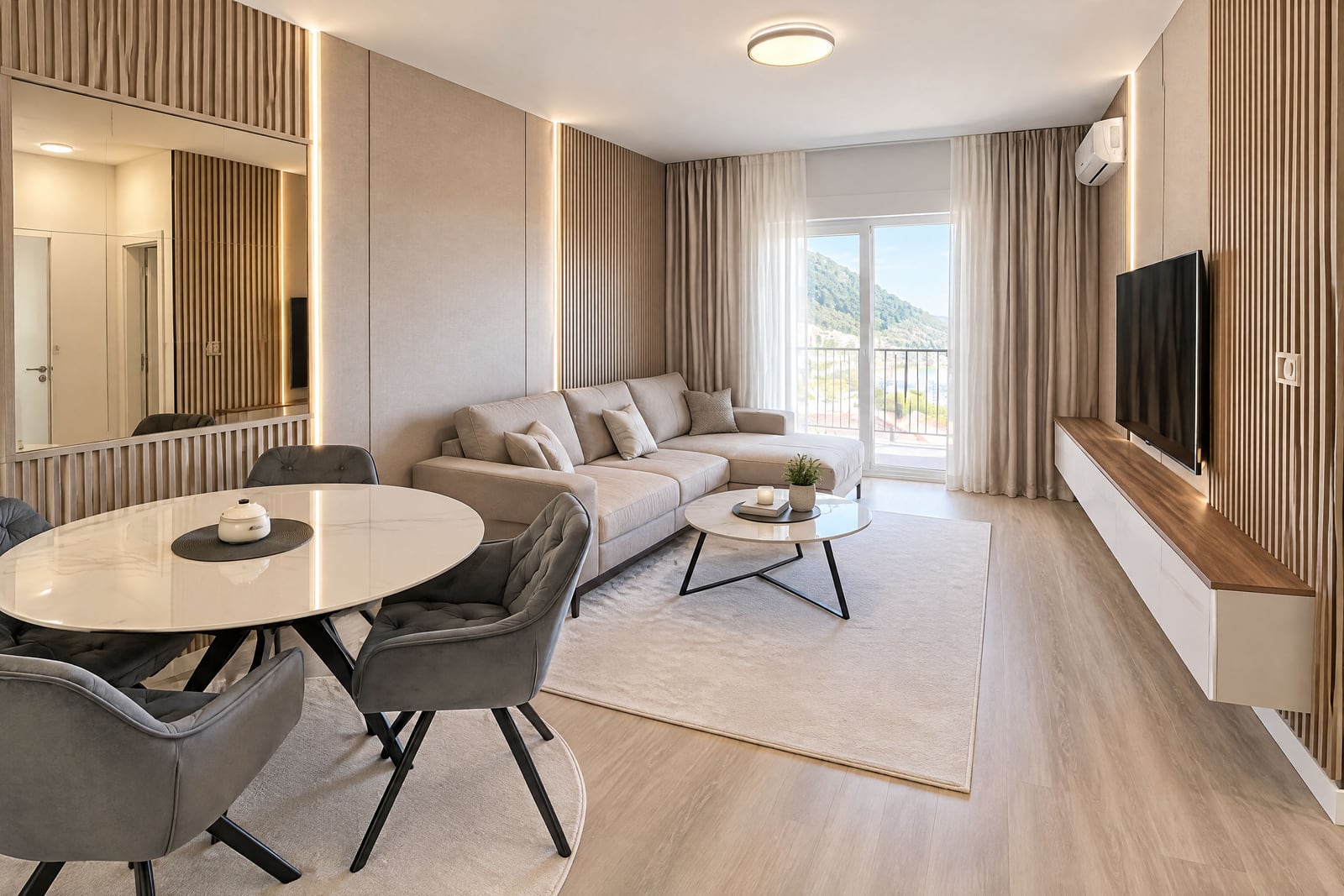 Modern living room with a sofa, dining area, and mountain views in an apartment in Budva, Montenegro