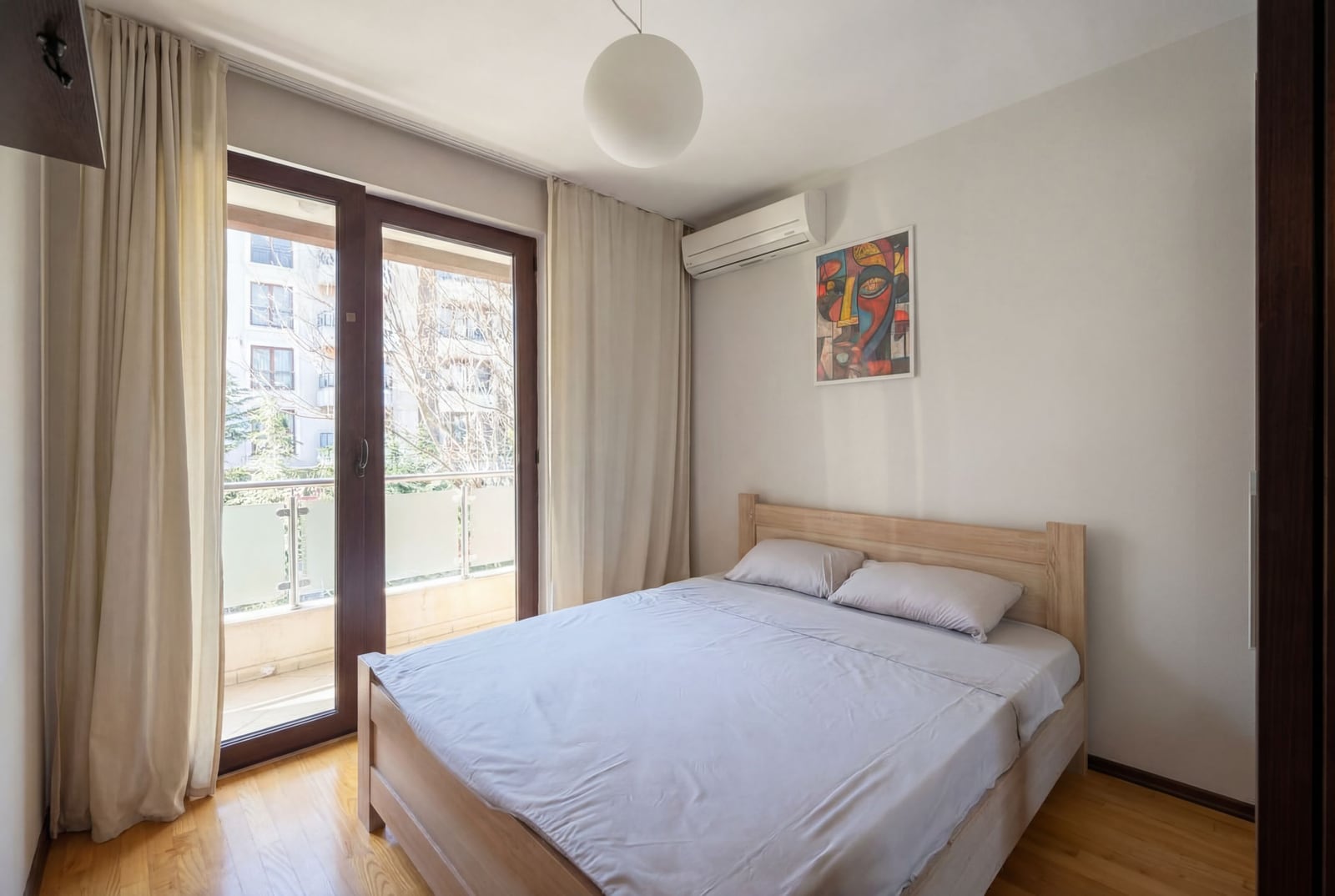 Svetla spavaća soba sa bračnim krevetom i izlazom na balkon u stanu, Budva, Crna Gora.
