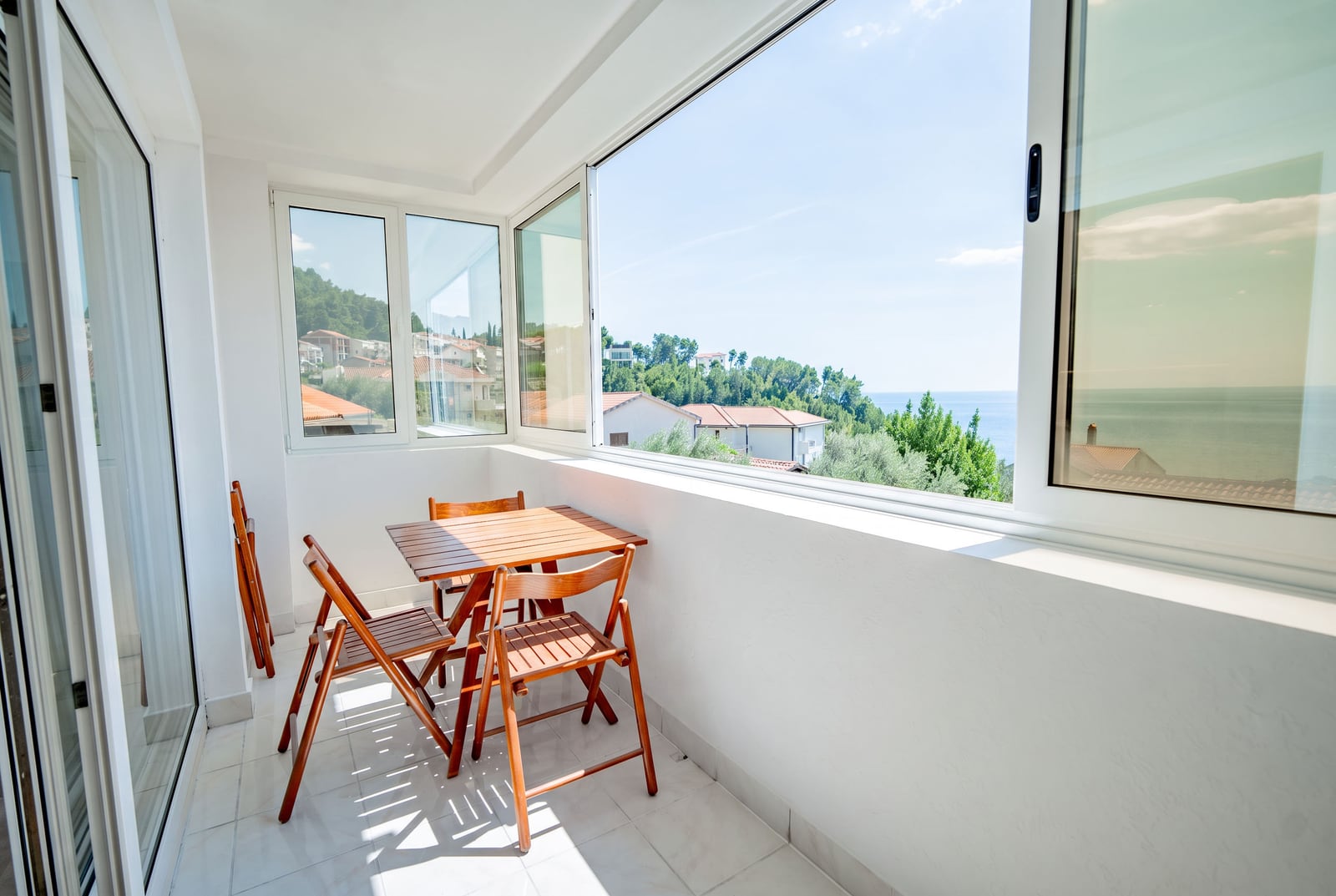 Balcony with wooden furniture and panoramic sea view in an apartment, Sveti Stefan, Montenegro.