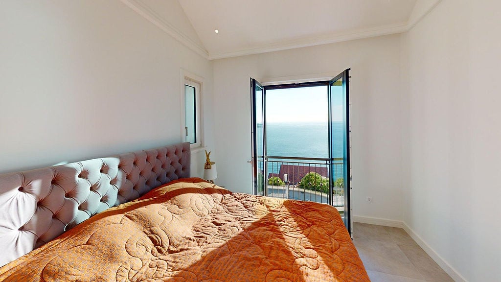 Schlafzimmer in einer Wohnung in Luštica, Montenegro: Doppelbett mit gepolstertem Kopfteil und Panoramablick auf die Adria.