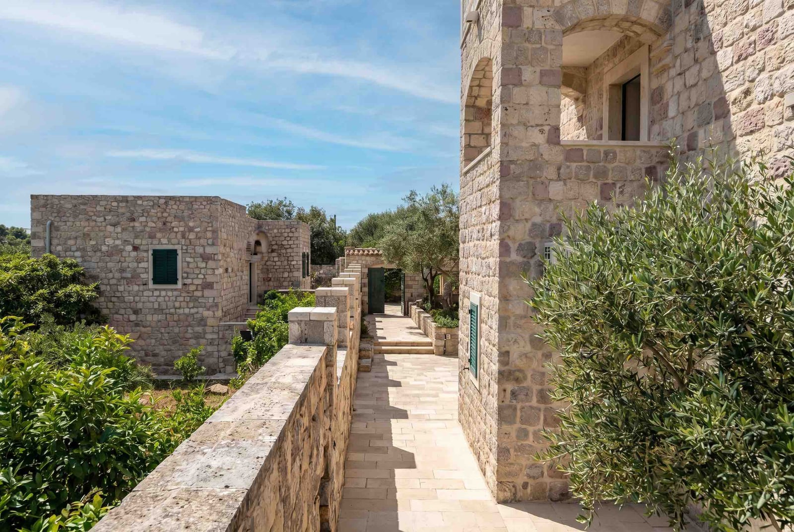 Kamenita kuća u mediteranskom stilu sa terasom i baštom u Luštici, Crna Gora. Pogled na fasadu i unutrašnje dvorište.
