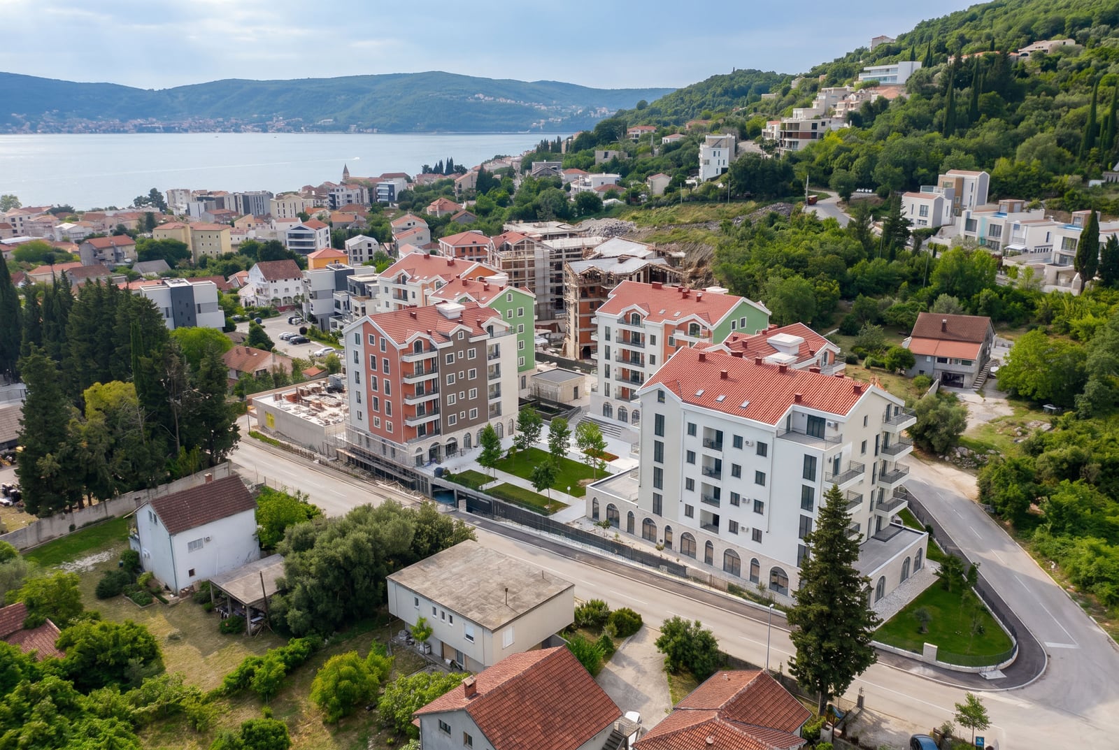 Aerial view of modern residential buildings with red roofs and landscaped grounds in Tivat, Montenegro.