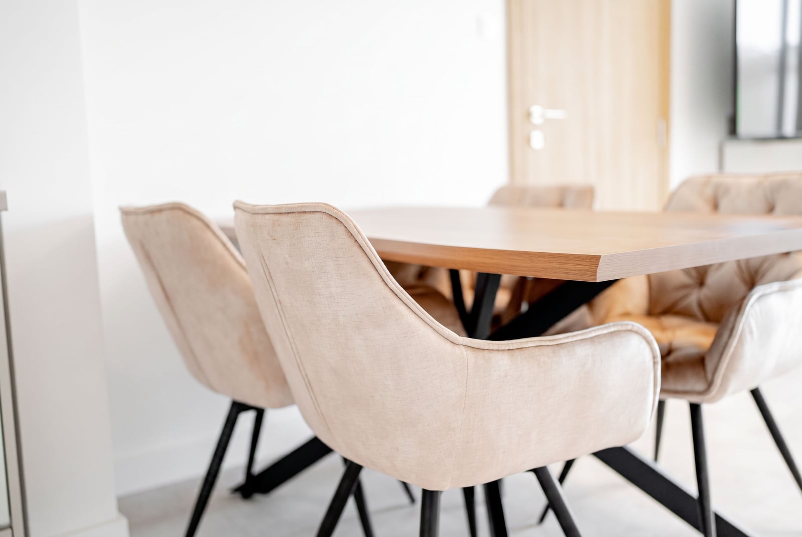 Modern dining area with beige chairs and a wooden table in an apartment, Sveti Stefan, Montenegro.