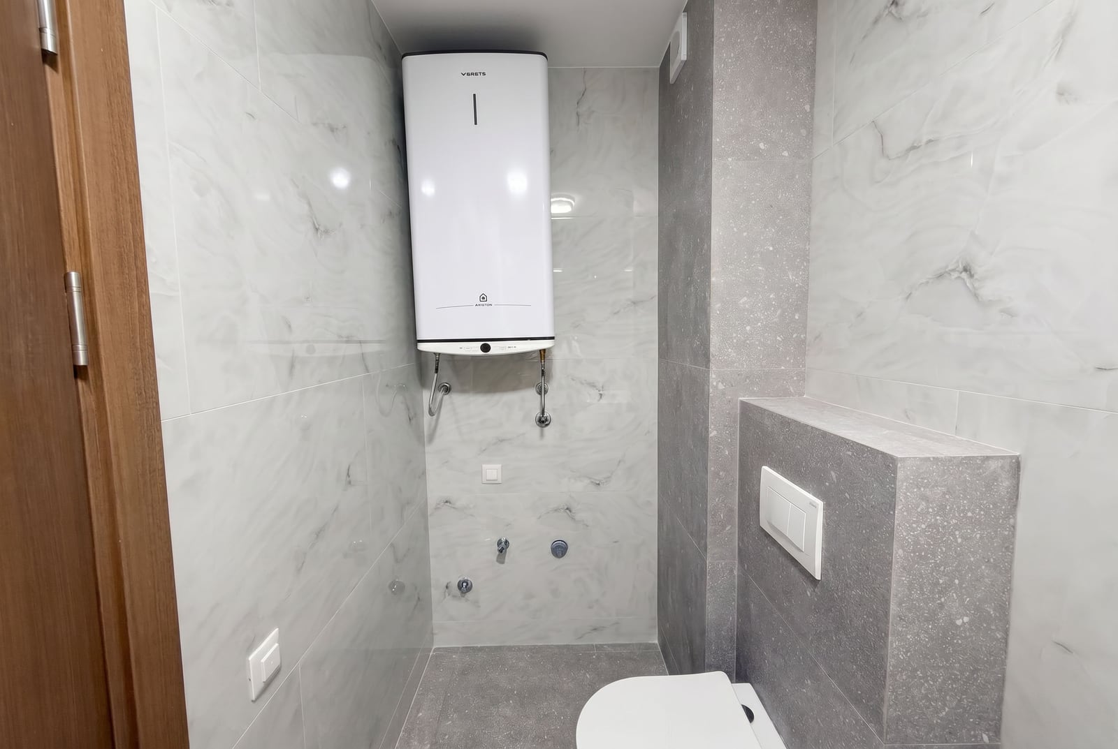 Karadağ, Budva'daki bir dairede, şofben ve fayans kaplamalı modern banyo.