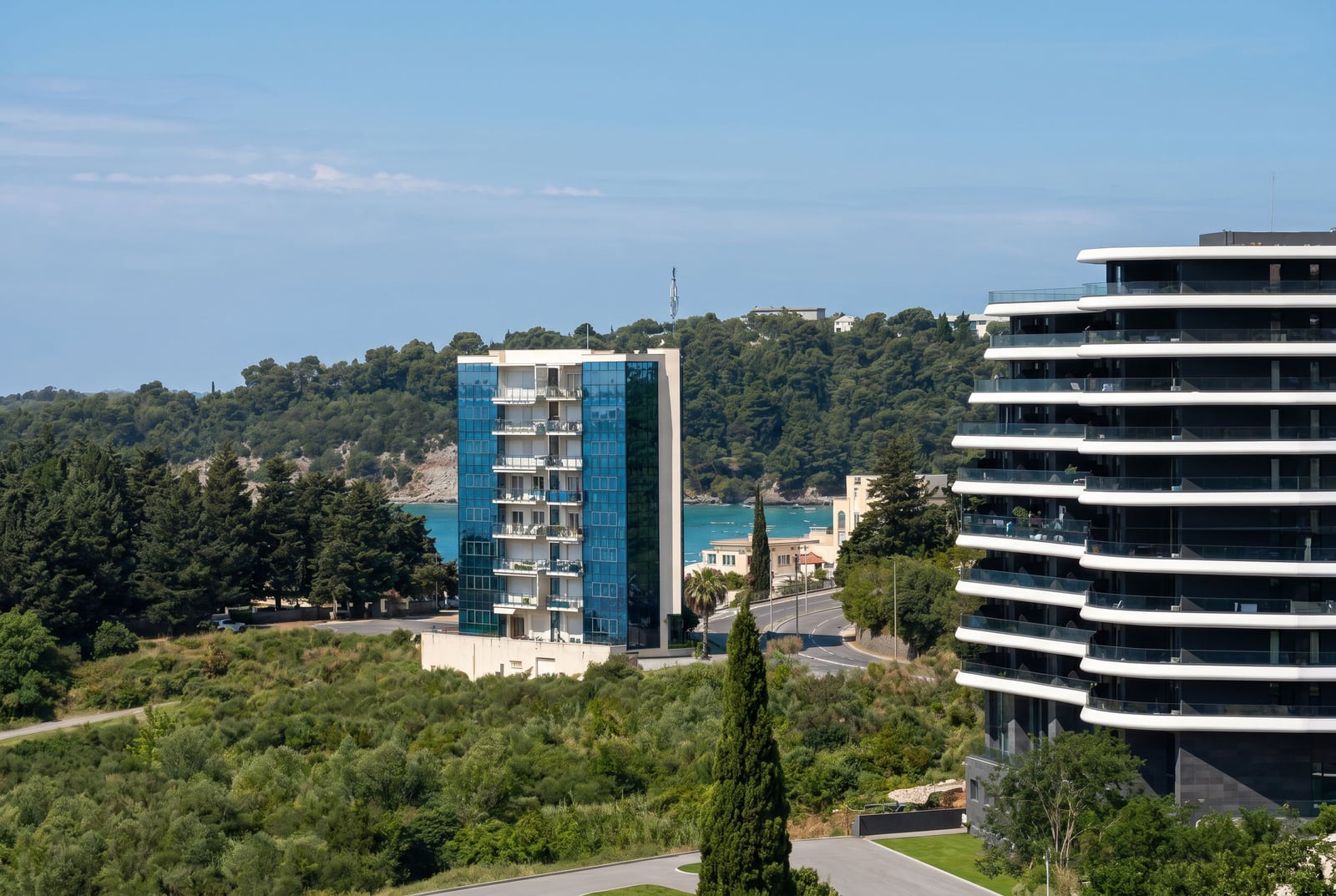 Modern residential complexes with panoramic windows in Bečići, Montenegro, aerial view of the sea and green hills.