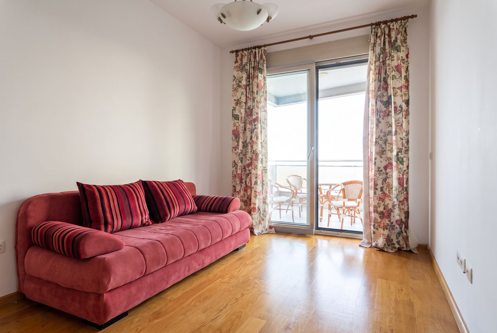 Living room with a red sofa and balcony access in an apartment in Bečići, Montenegro