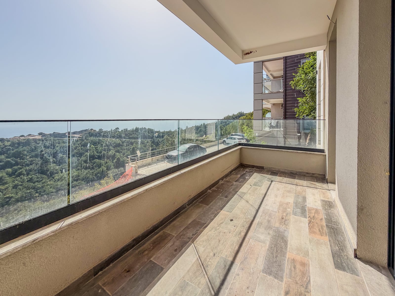 Spacious balcony with panoramic glazing and wood-finish detailing in a new development in Budva, Montenegro
