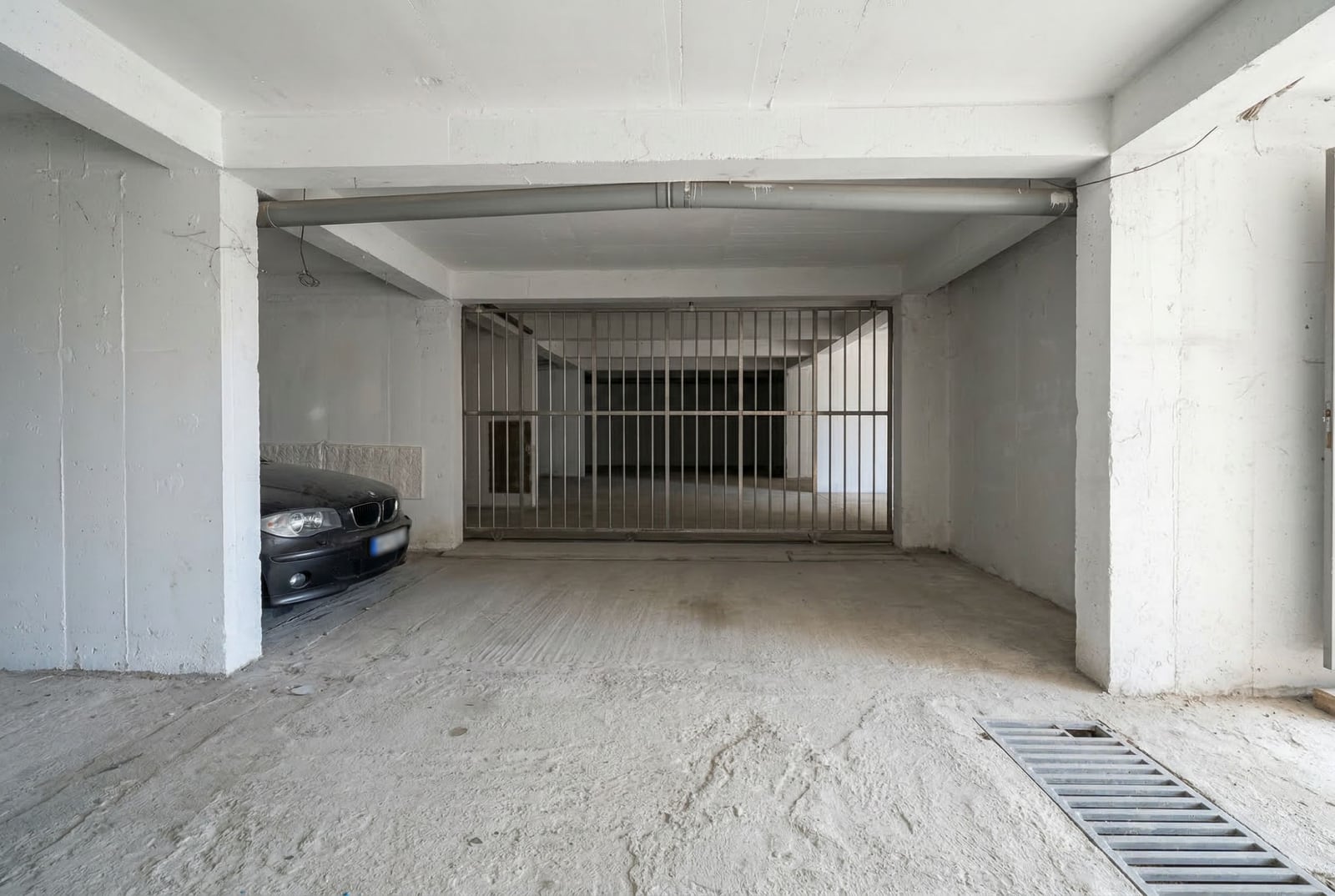 Natkriveno parking mesto u stambenom kompleksu u Budvi, Crna Gora: betonska garaža sa metalnom rešetkom.