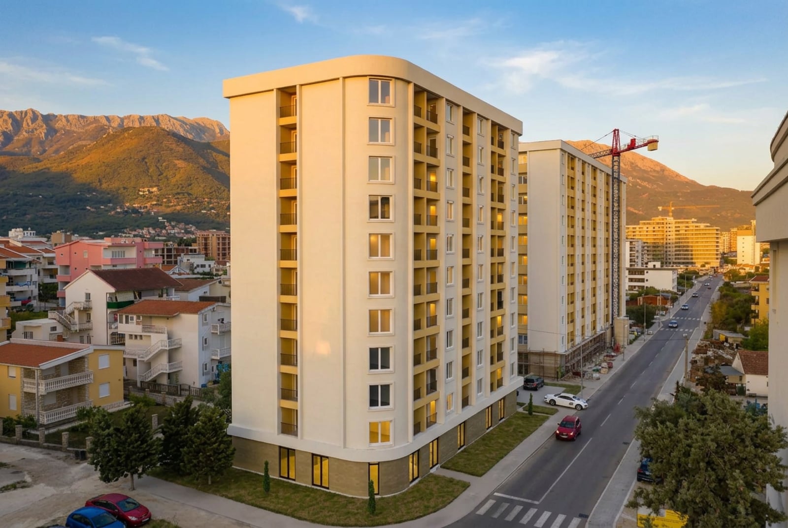 Neuer Wohnkomplex in der Stadt Bar, Montenegro: modernes mehrstöckiges Gebäude mit Balkonen vor Bergkulisse.