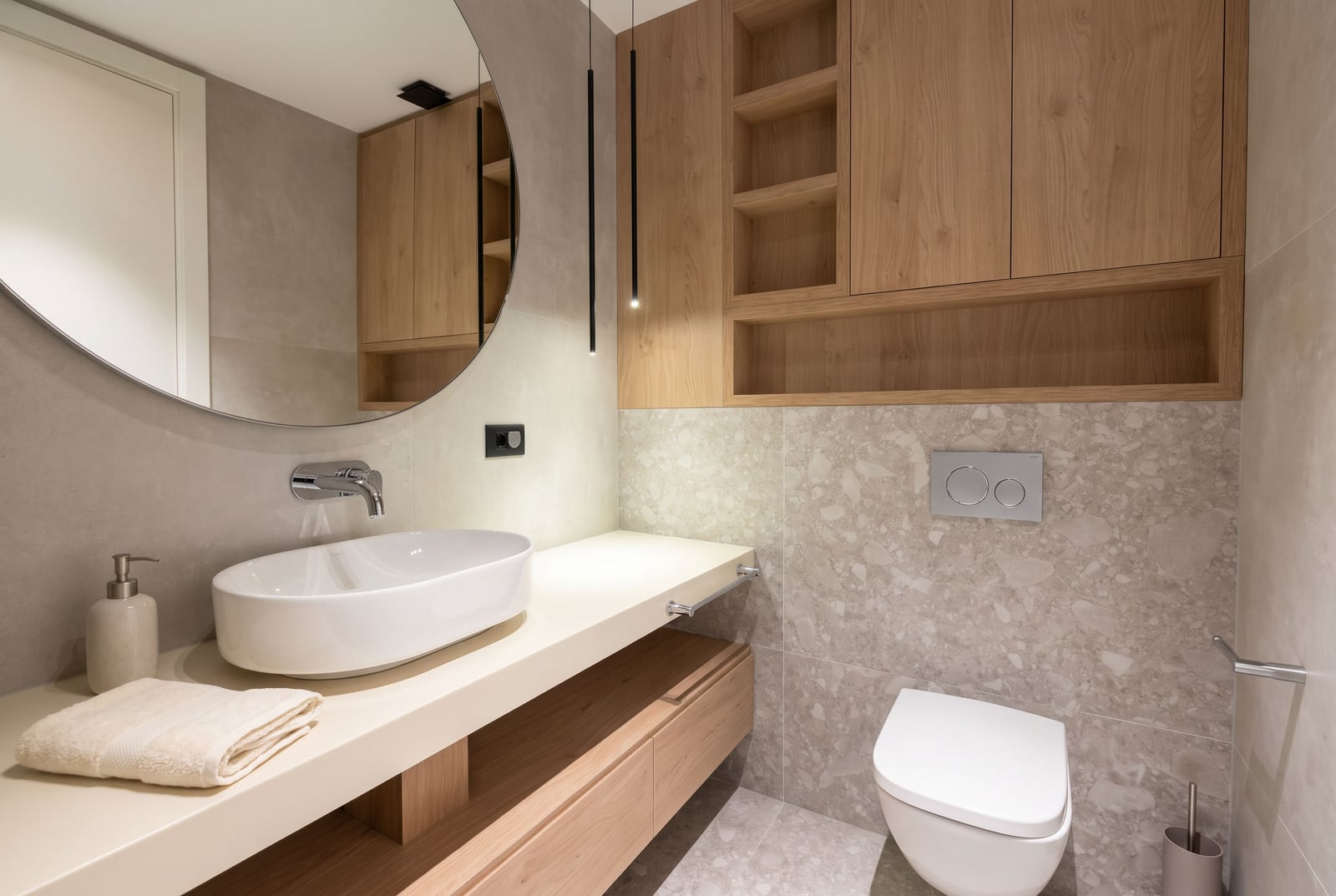 Modern bathroom with a sink, round mirror, and wooden furniture in an apartment in Budva, Montenegro