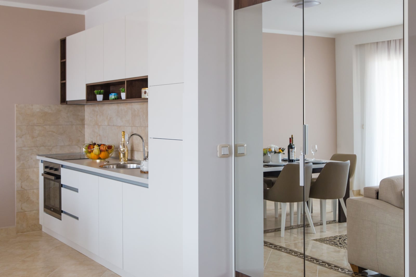 Moderne weiße Küche und Essbereich in einer Wohnung in Bečići, Montenegro: stilvolles Interieur mit hochwertiger Ausstattung.