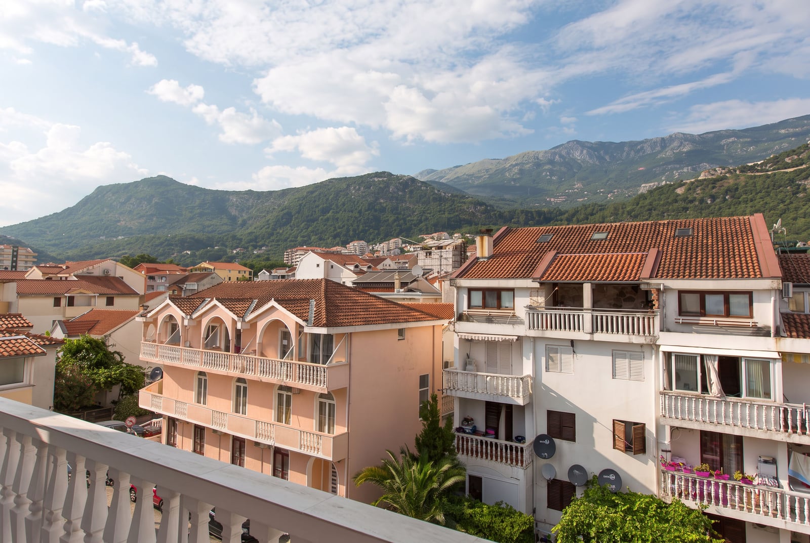 View of tiled roofs and green mountains from the balcony of an apartment in Budva, Montenegro.