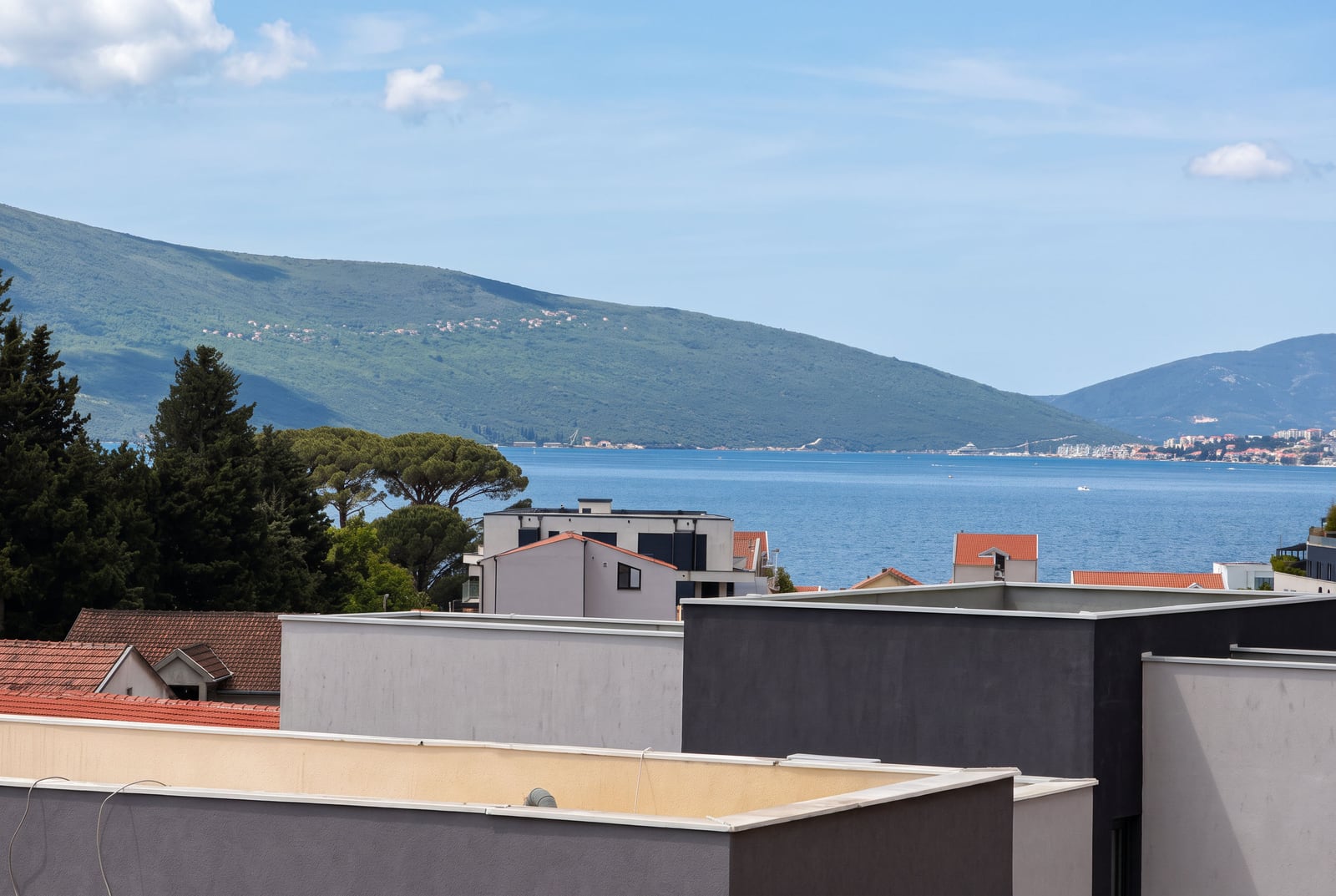 Panoramic view of the sea, mountains, and house rooftops from the balcony of an apartment in Tivat, Montenegro.
