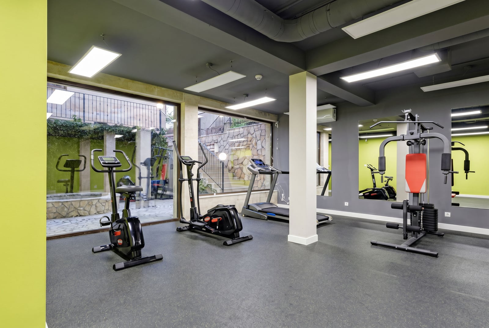 Modern gym with panoramic windows in a residential complex, Kumbor, Montenegro: cardio equipment and strength training area.
