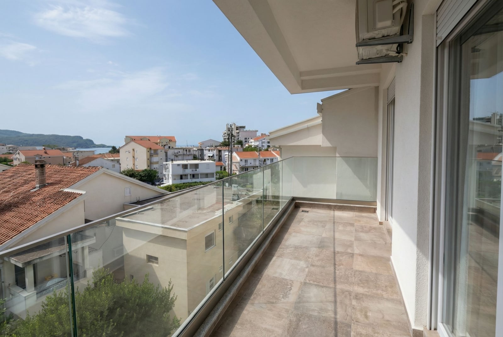 Prostran balkon sa panoramskim zastakljenjem i pogledom na more i grad u stanu, Budva, Crna Gora.
