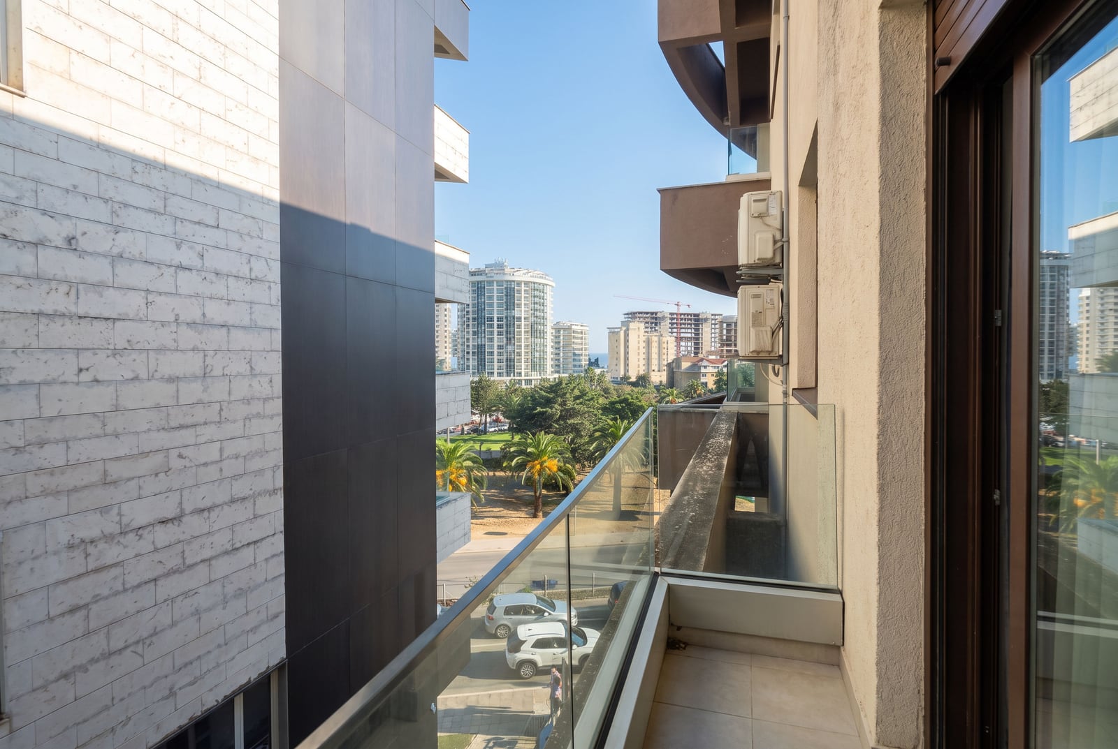 Blick vom Balkon einer modernen Wohnung in Budva, Montenegro, auf die Stadt und Palmen