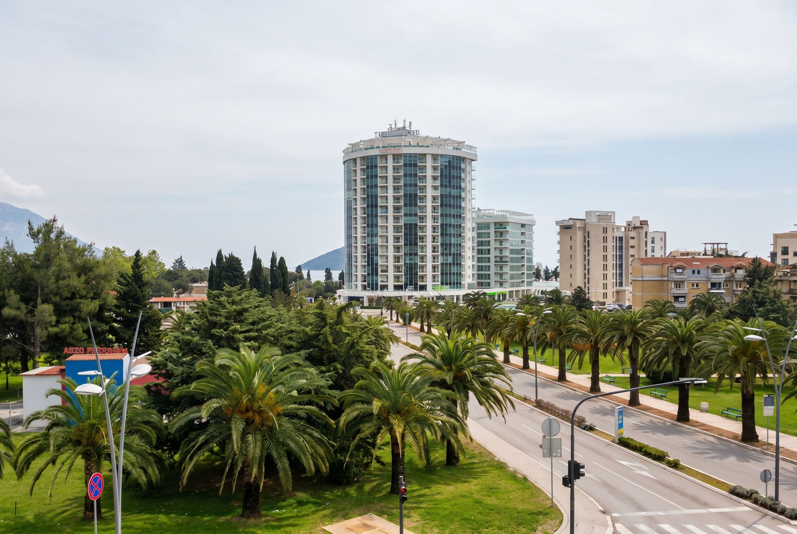 View of a modern residential complex with palm trees and a road in Budva, Montenegro: panorama of the city and the coastline.