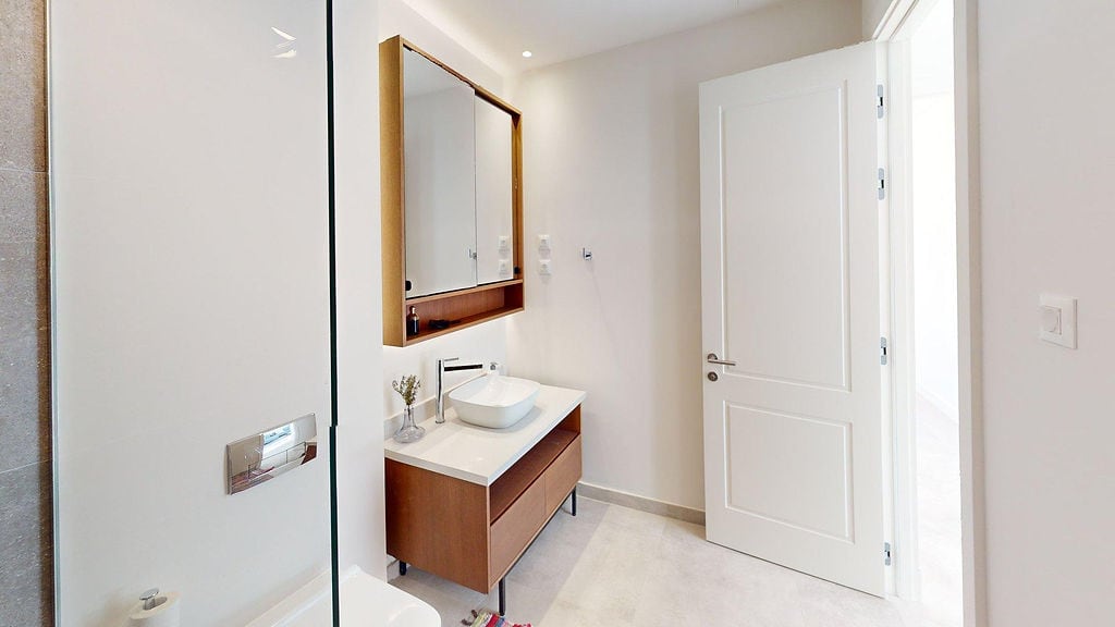 Modernes Badezimmer mit Holzunterschrank und Spiegel in der Wohnung Lustica Bay, Luštica, Montenegro.