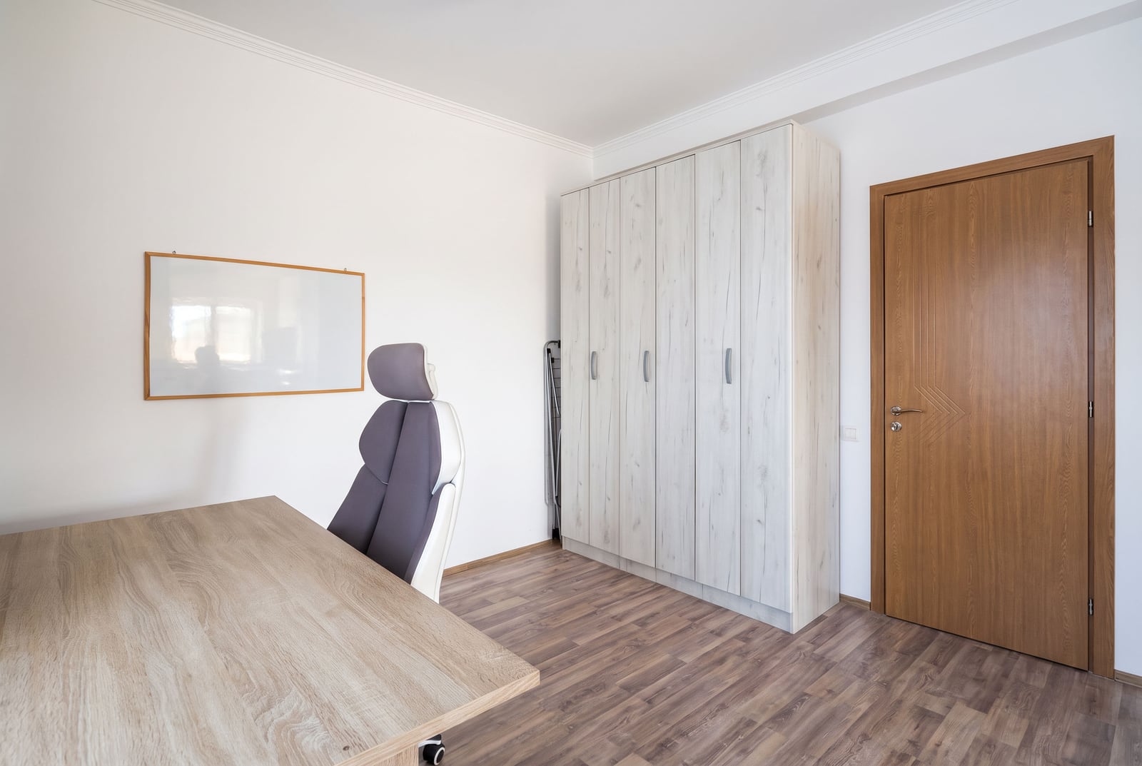 Radna zona u spavaćoj sobi apartmana u Tivtu, Crna Gora: pisaci sto, stolica, svetli orman i laminat.