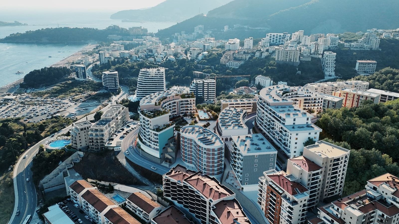 Karadağ, Bečići’deki konut kompleksinin havadan görünümü: modern binalar, yüzme havuzları ve Adriyatik kıyısının panoraması.
