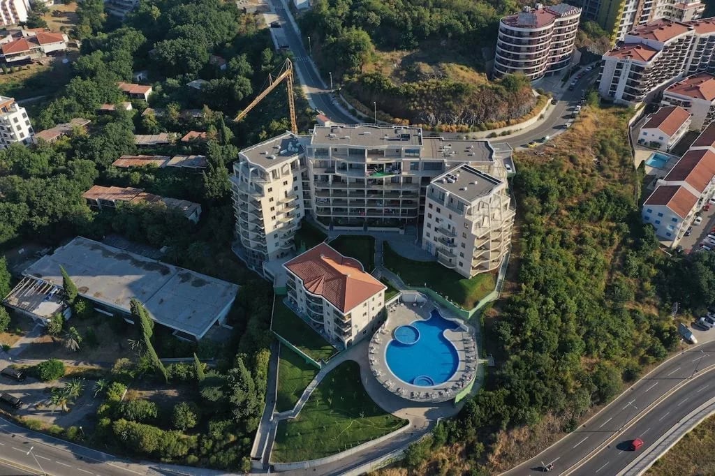 Aerial view of a residential complex with a swimming pool and landscaped grounds in Bečići, Montenegro.