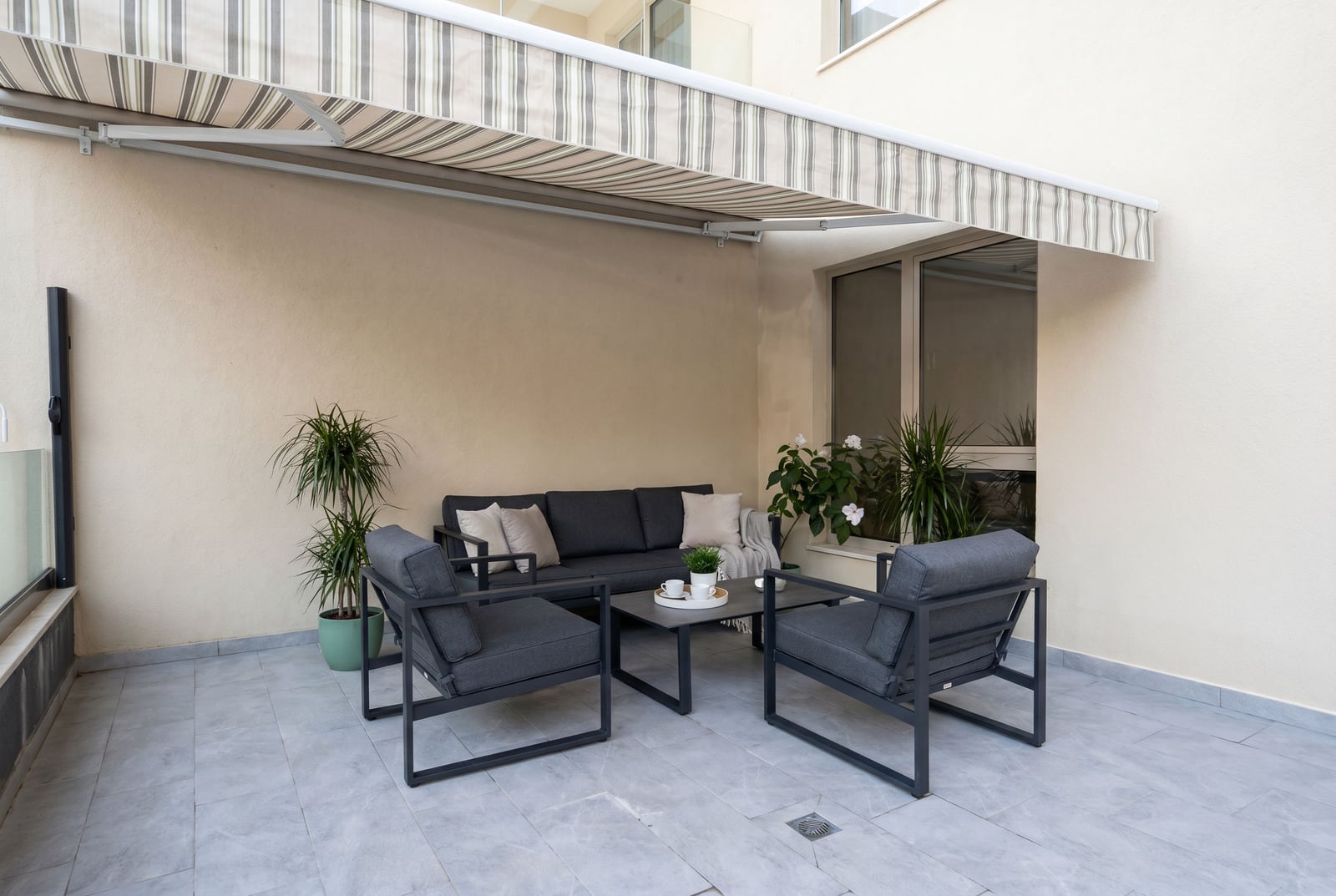 Udobna terasa sa baštenskim nameštajem i tendom u stanu, Bečići, Crna Gora. Moderan balkon sa prostorom za odmor.