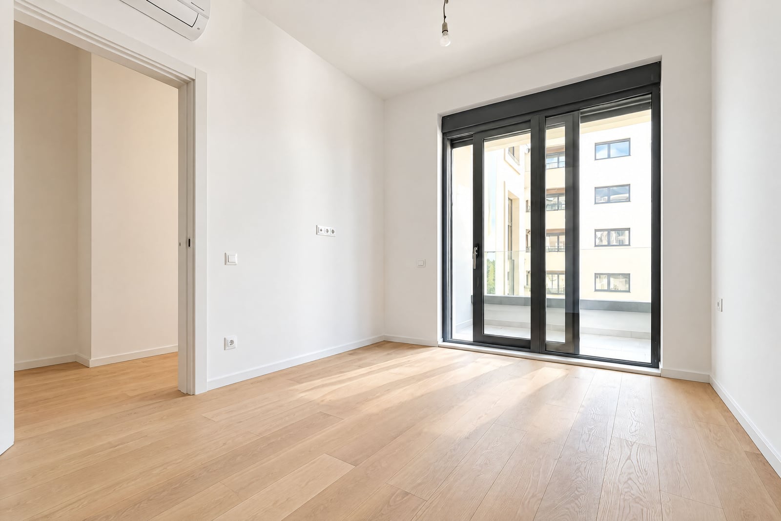 Bright empty bedroom with a panoramic window and parquet flooring in a new apartment in Becici, Montenegro