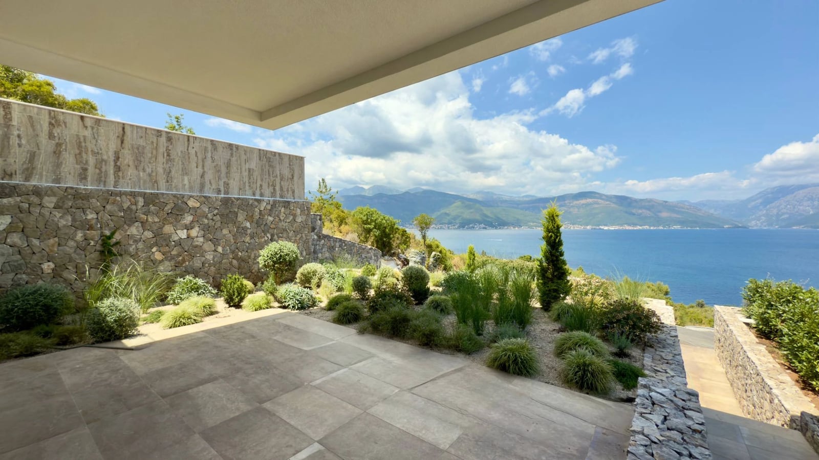 Terrasse der Villa in Krašići, Montenegro: Steinverkleidung, Landschaftsgestaltung und Panoramablick auf das Meer und die Berge.