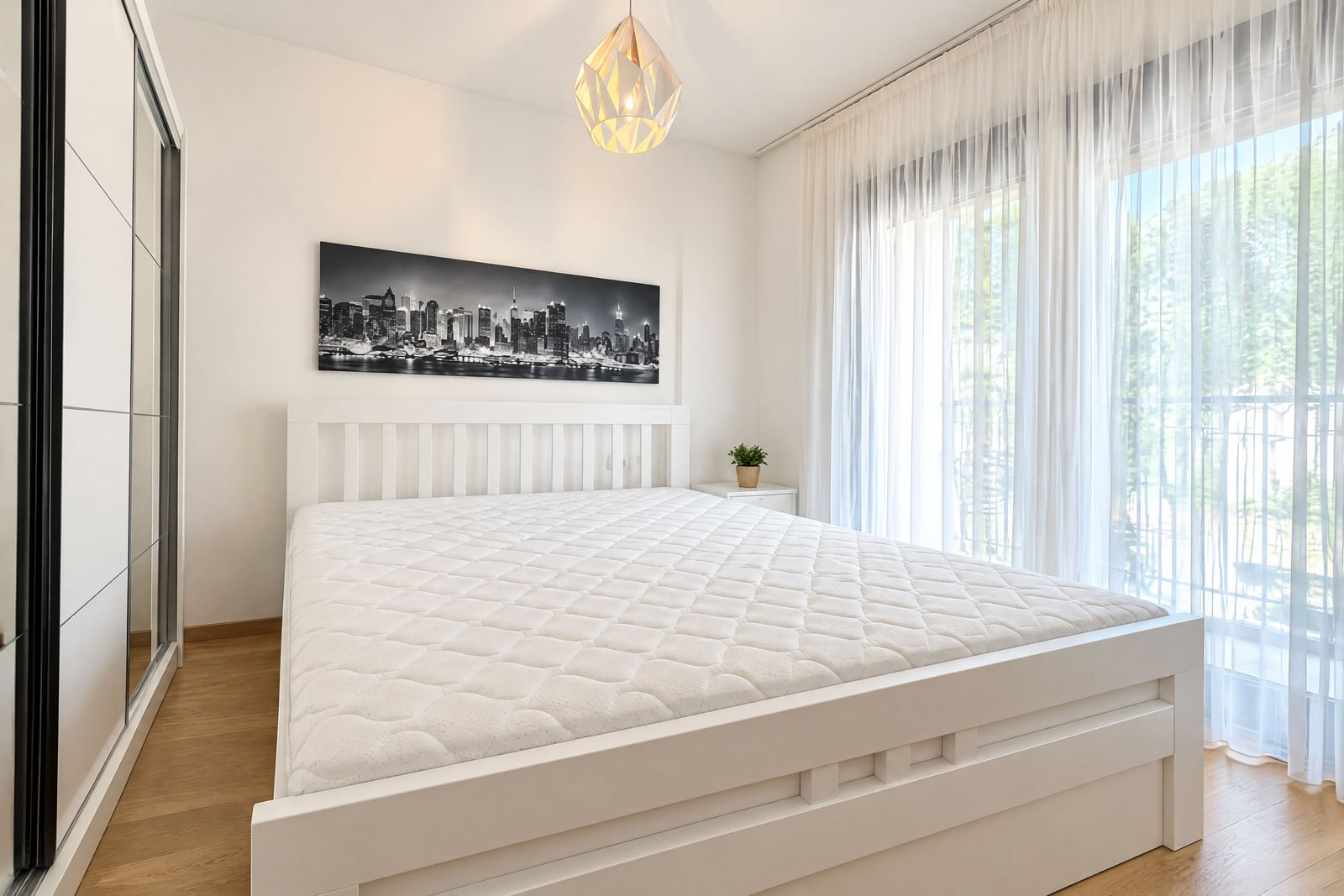Bright bedroom with white furniture, a double bed, and a panoramic window in an apartment in Budva, Montenegro