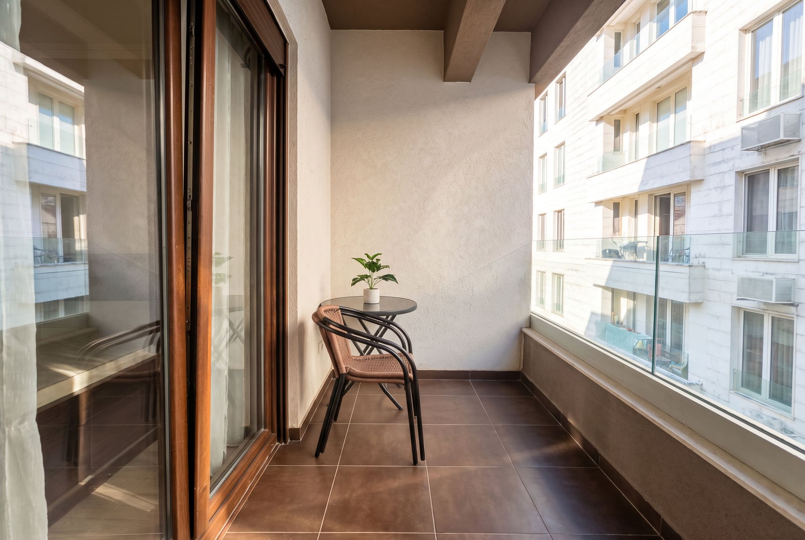Geräumiger Balkon mit Fliesen, Korbstühlen, Tisch und Glasgeländer in einer Wohnung in Budva, Montenegro