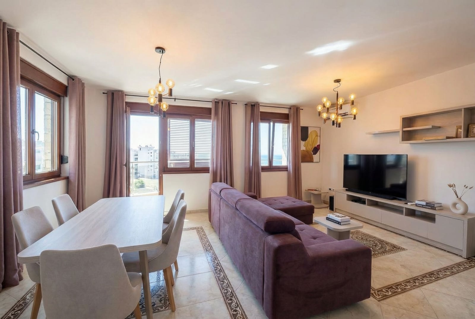 Jasny salon z fioletową sofą i jadalnią w apartamencie w Rafailovici, Czarnogóra, widok na morze.