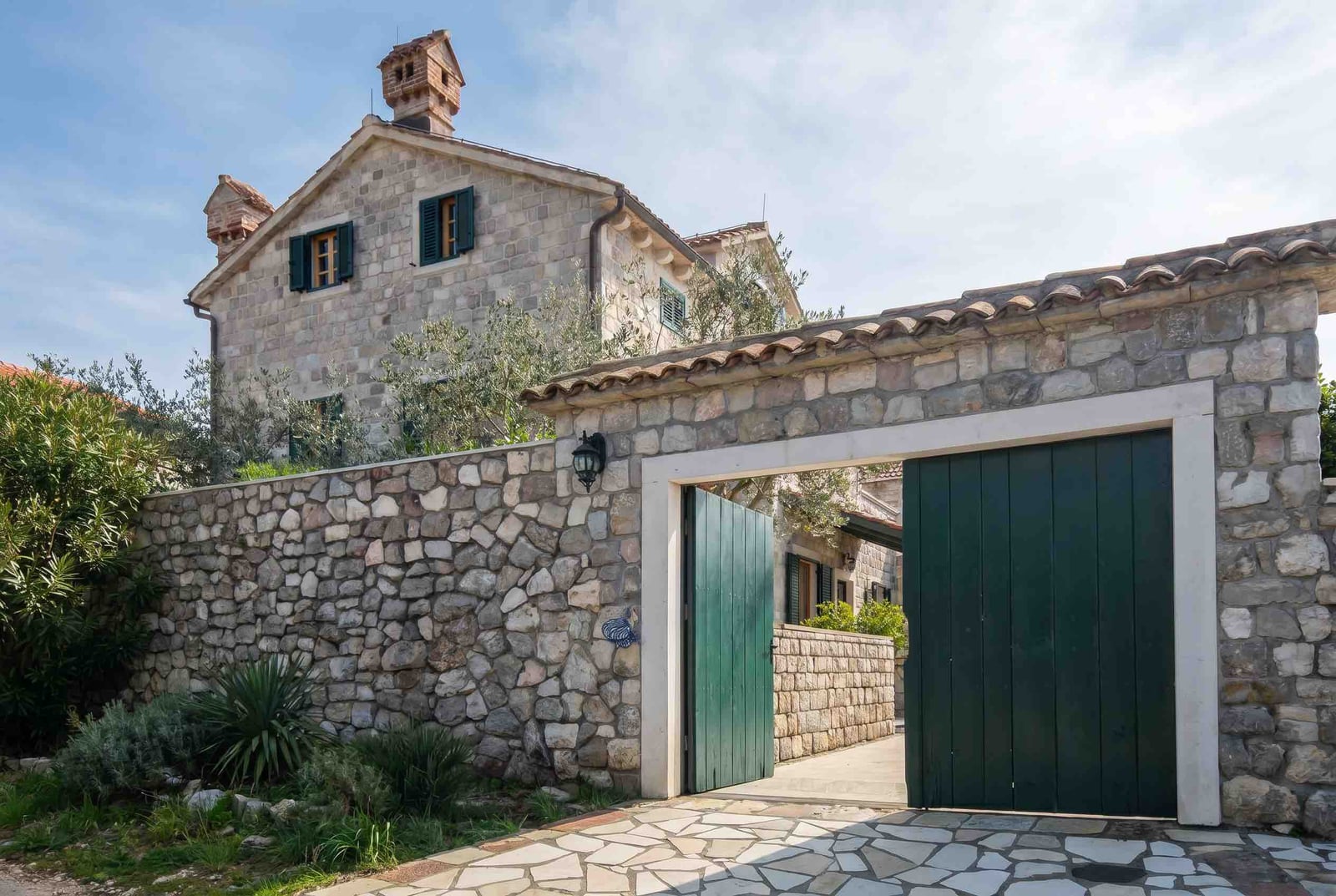 Kamenita kuća u mediteranskom stilu sa zelenim kapijama i baštom, Luštica, Crna Gora.