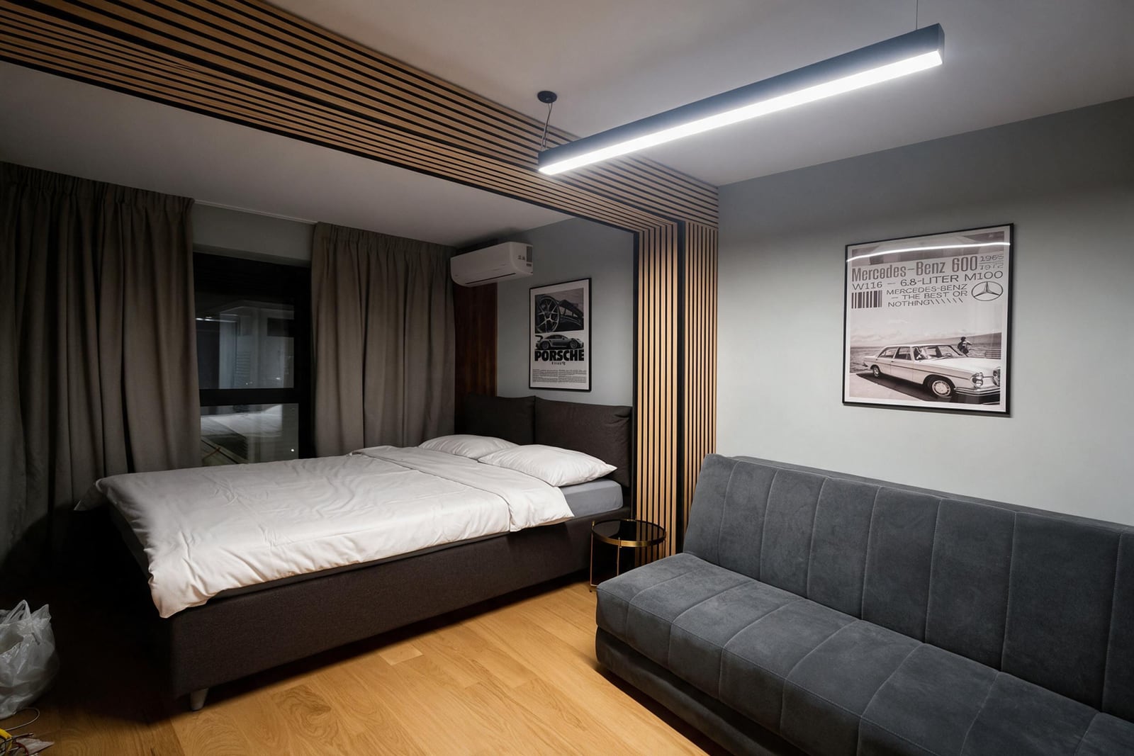 Modern bedroom with wooden slats, a double bed, and a gray sofa in an apartment in Budva, Montenegro