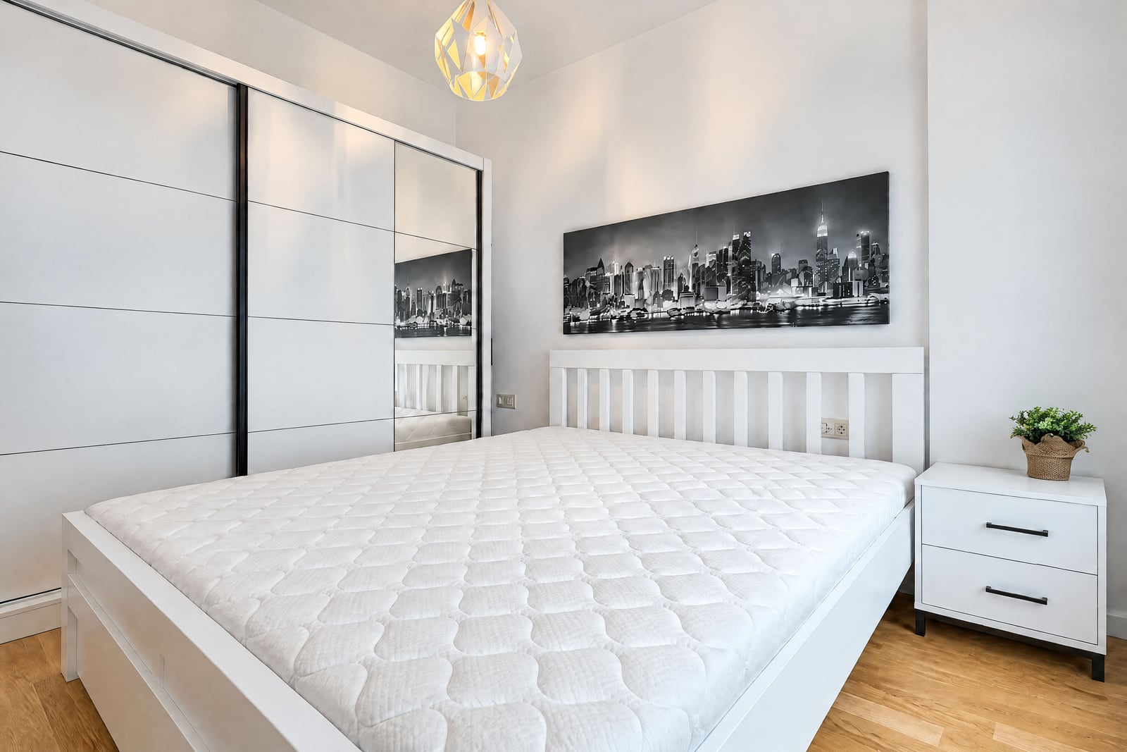 Bright bedroom with a large bed, a built-in wardrobe, and a painting in an apartment in Budva, Montenegro