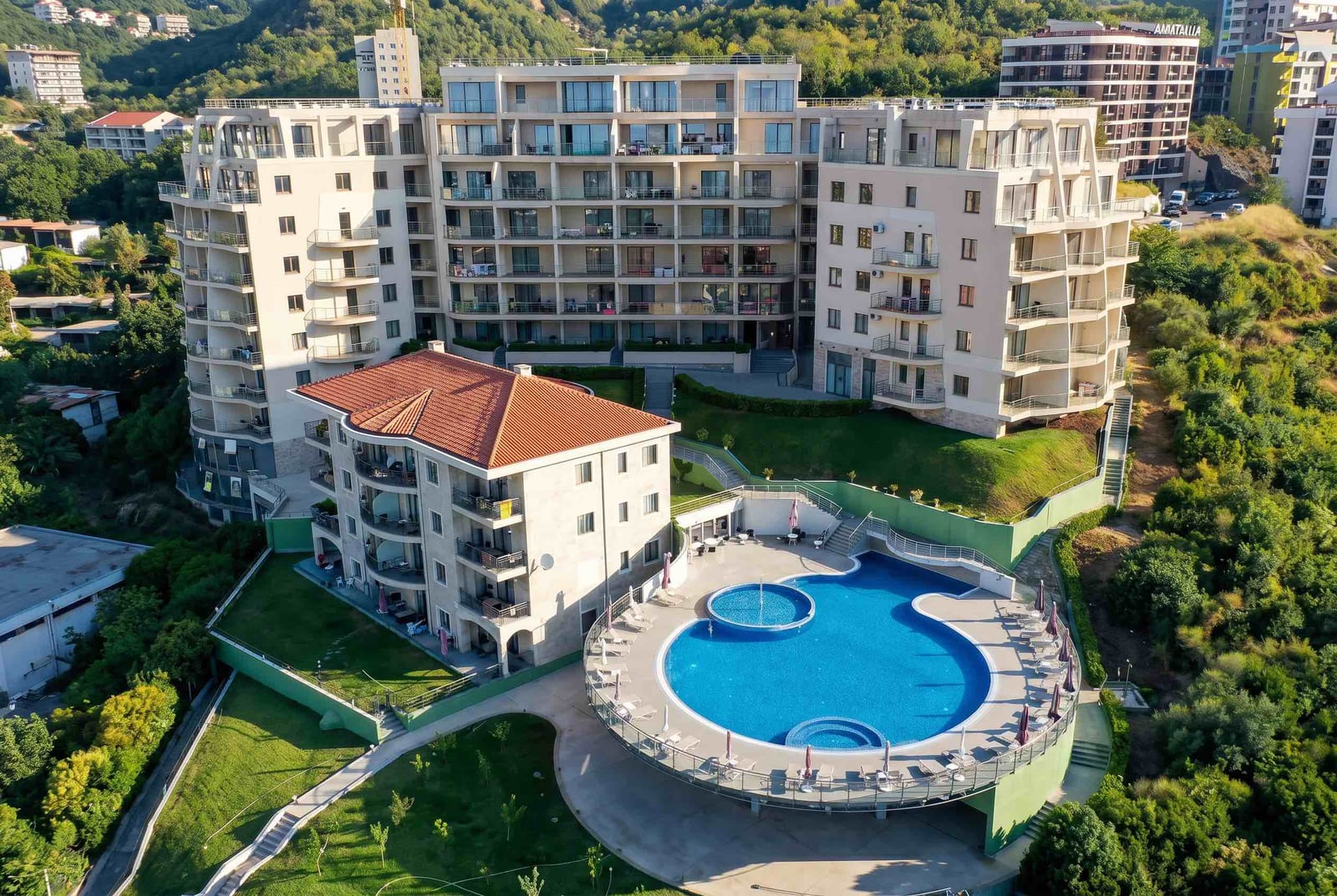 Residential complex with a pool in Bečići, Montenegro: view of modern multi-story buildings and landscaped grounds.