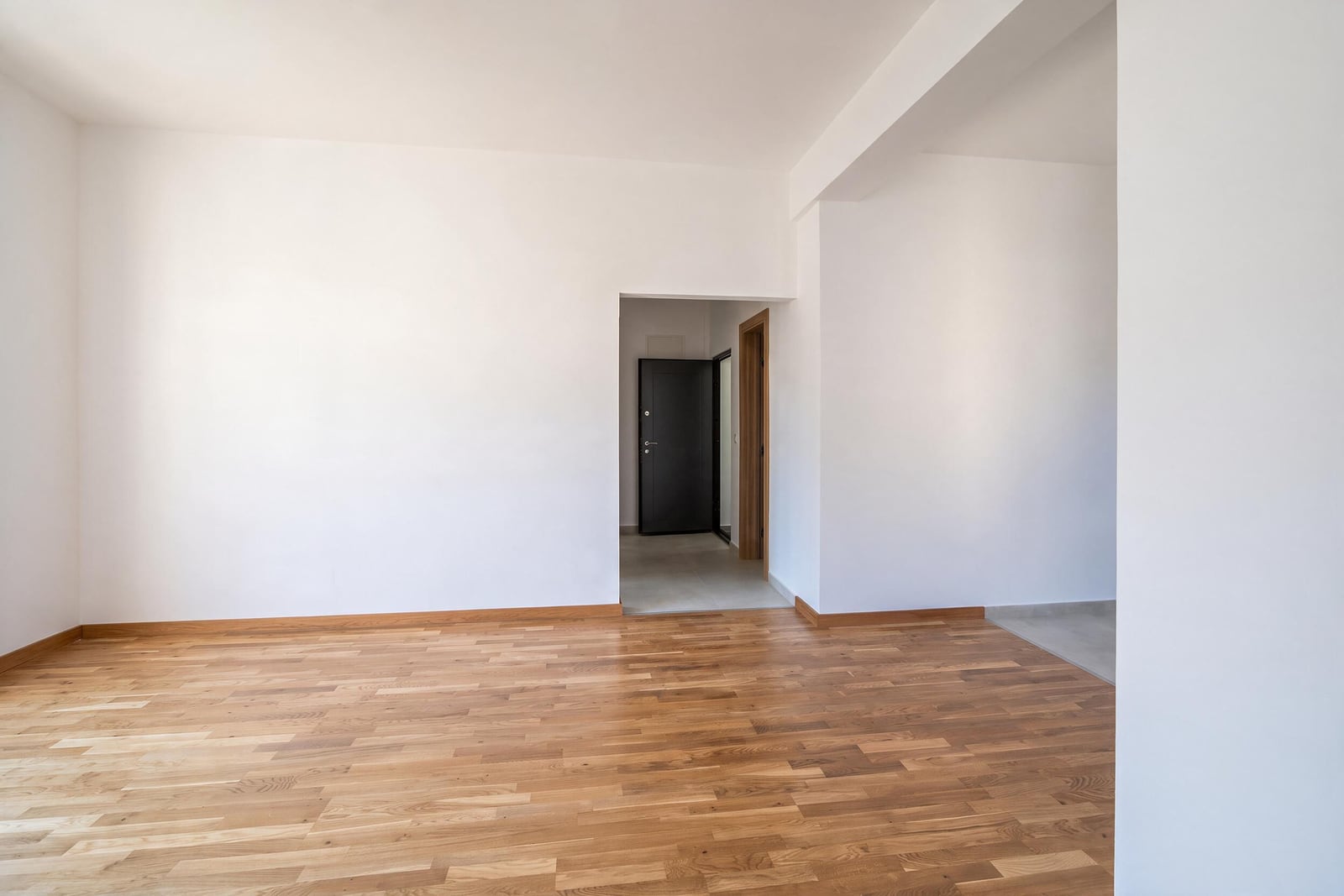 Bright living room with parquet flooring and white walls in an apartment, Bar, Montenegro. View of the entrance area.