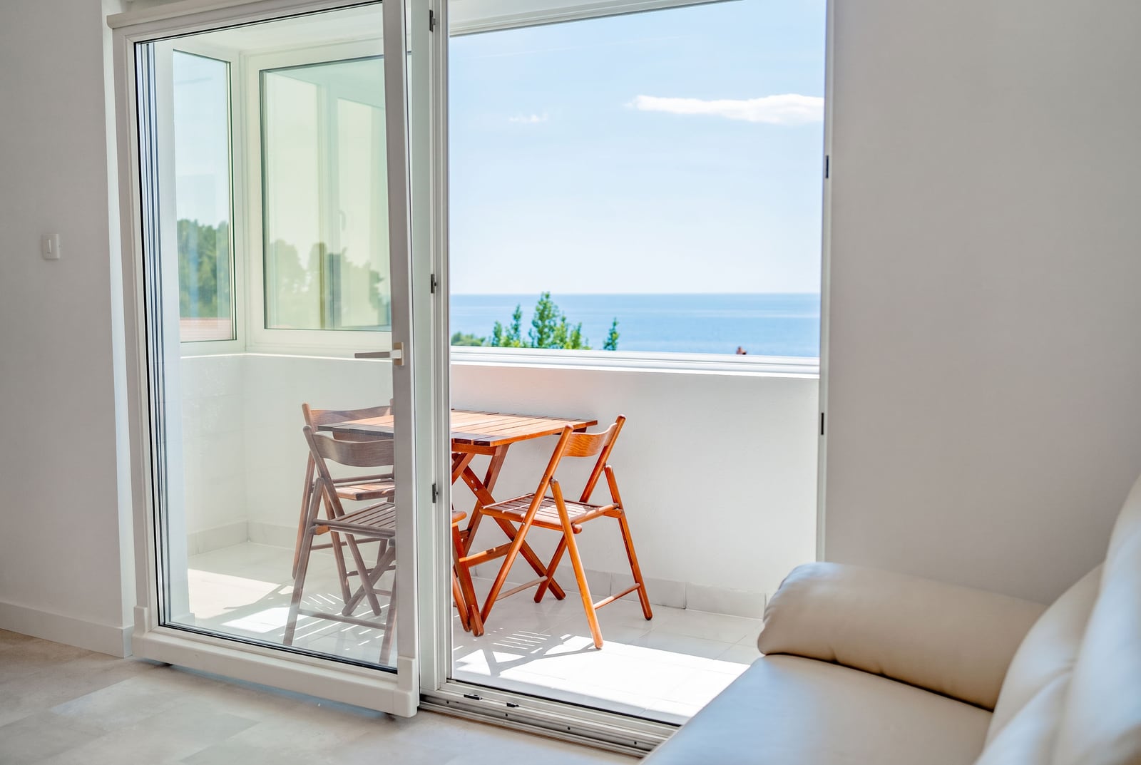 View from the balcony of an apartment in Sveti Stefan, Montenegro: wooden furniture, panoramic sea view, and a bright interior.