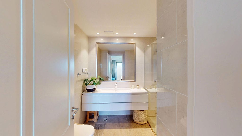 Karadağ, Luštica konut kompleksindeki dairede beyaz dolap ve aynalı modern banyo. Kaliteli fayans işçiliği.