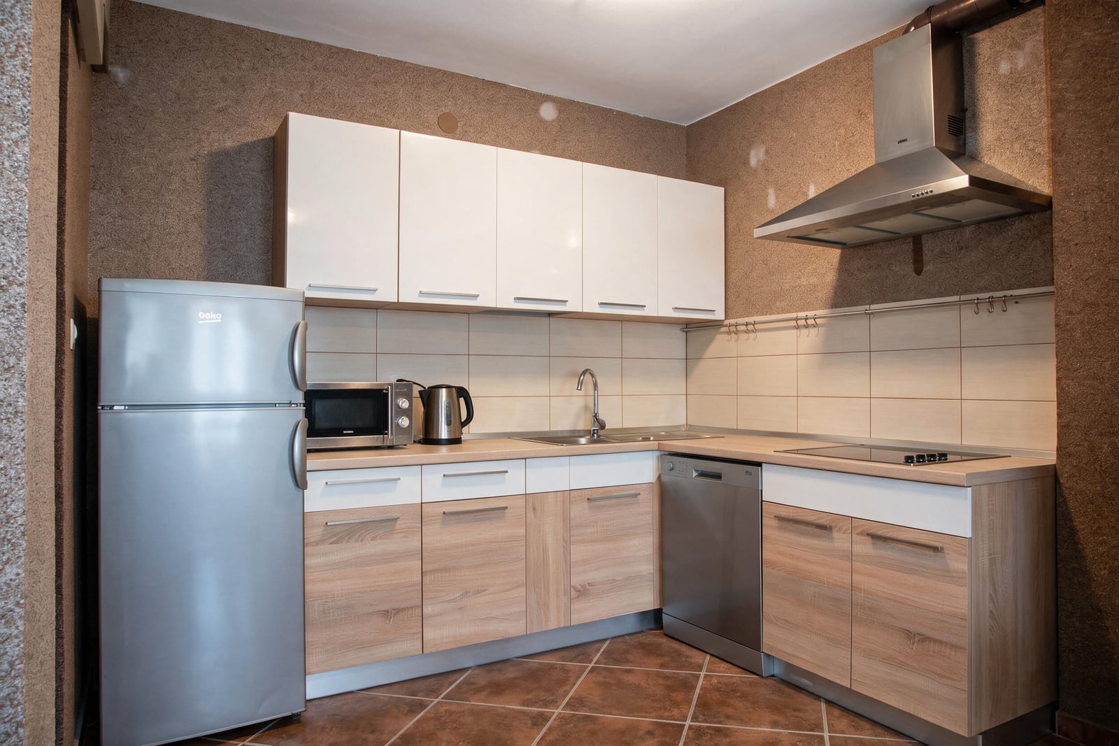 Modern corner kitchen with wood-style furniture, appliances, and a refrigerator in a house in Tivat, Montenegro