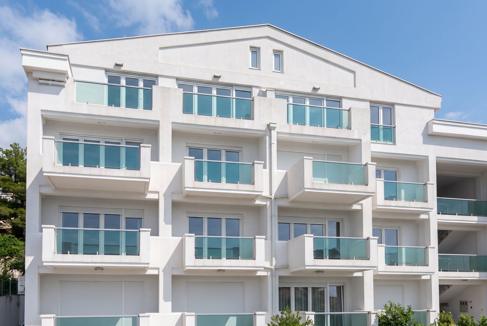 White facade of a modern apartment building with balconies and glass railings in Petrovac, Montenegro.