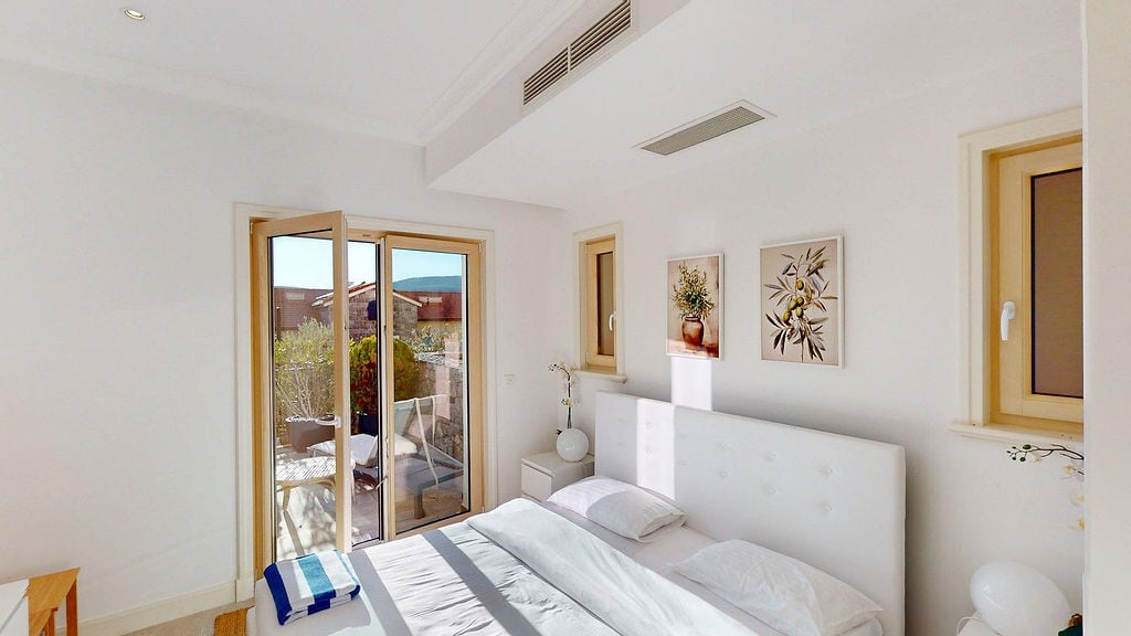 Helles Schlafzimmer in einer Wohnung in Luštica, Montenegro: Doppelbett, Zugang zur Terrasse und moderne Ausstattung.
