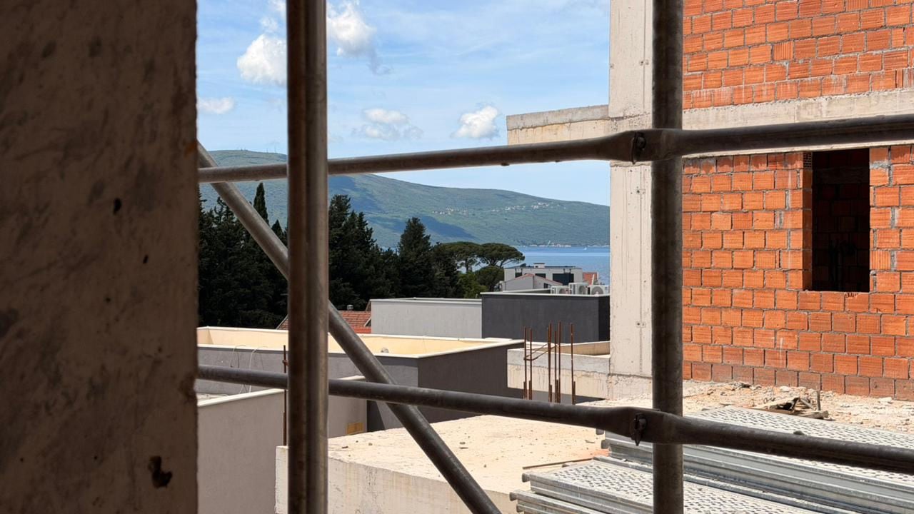 Sea and mountain view through the scaffolding of a house under construction in Tivat, Montenegro