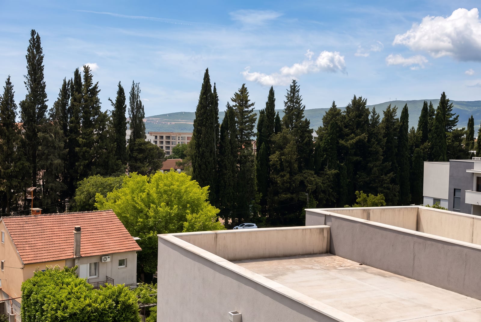 Panoramic view of the mountains, cypresses, and tiled rooftops from an apartment in Tivat, Montenegro.