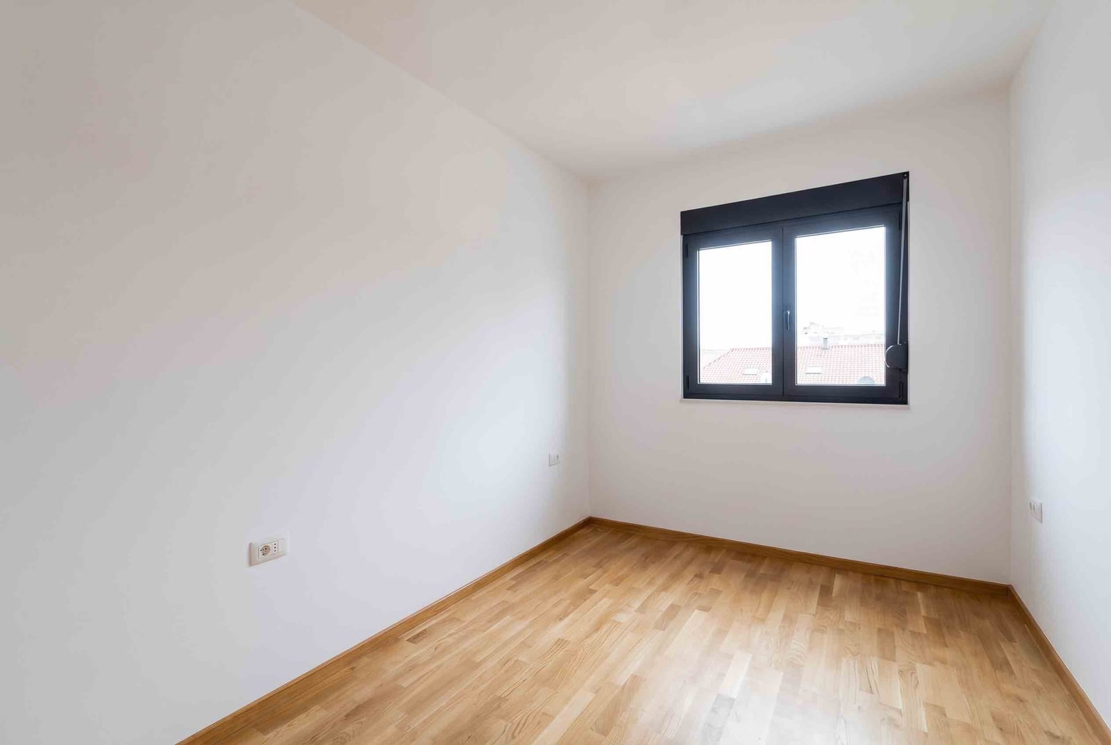 Bright empty bedroom with parquet flooring and a window in an apartment in Budva, Montenegro.