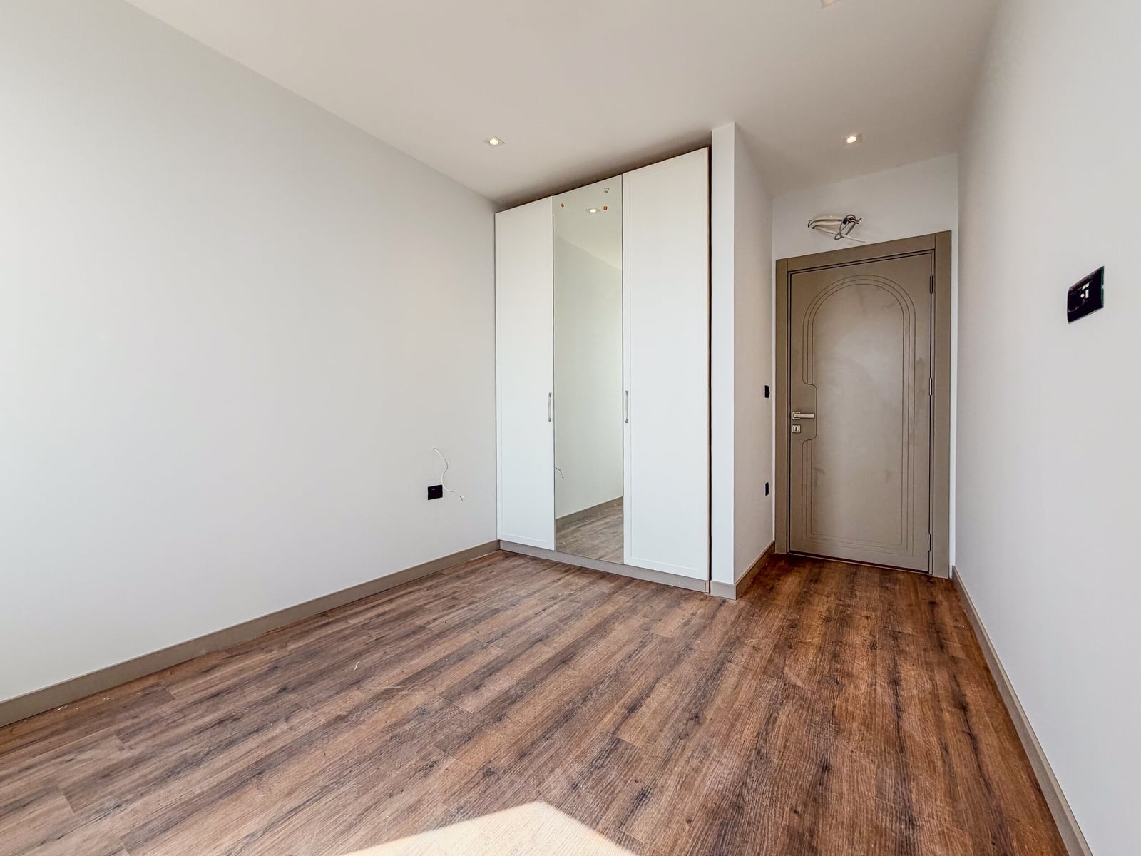 Bright bedroom with white walls, a built-in wardrobe, and laminate flooring in an apartment in Budva, Montenegro