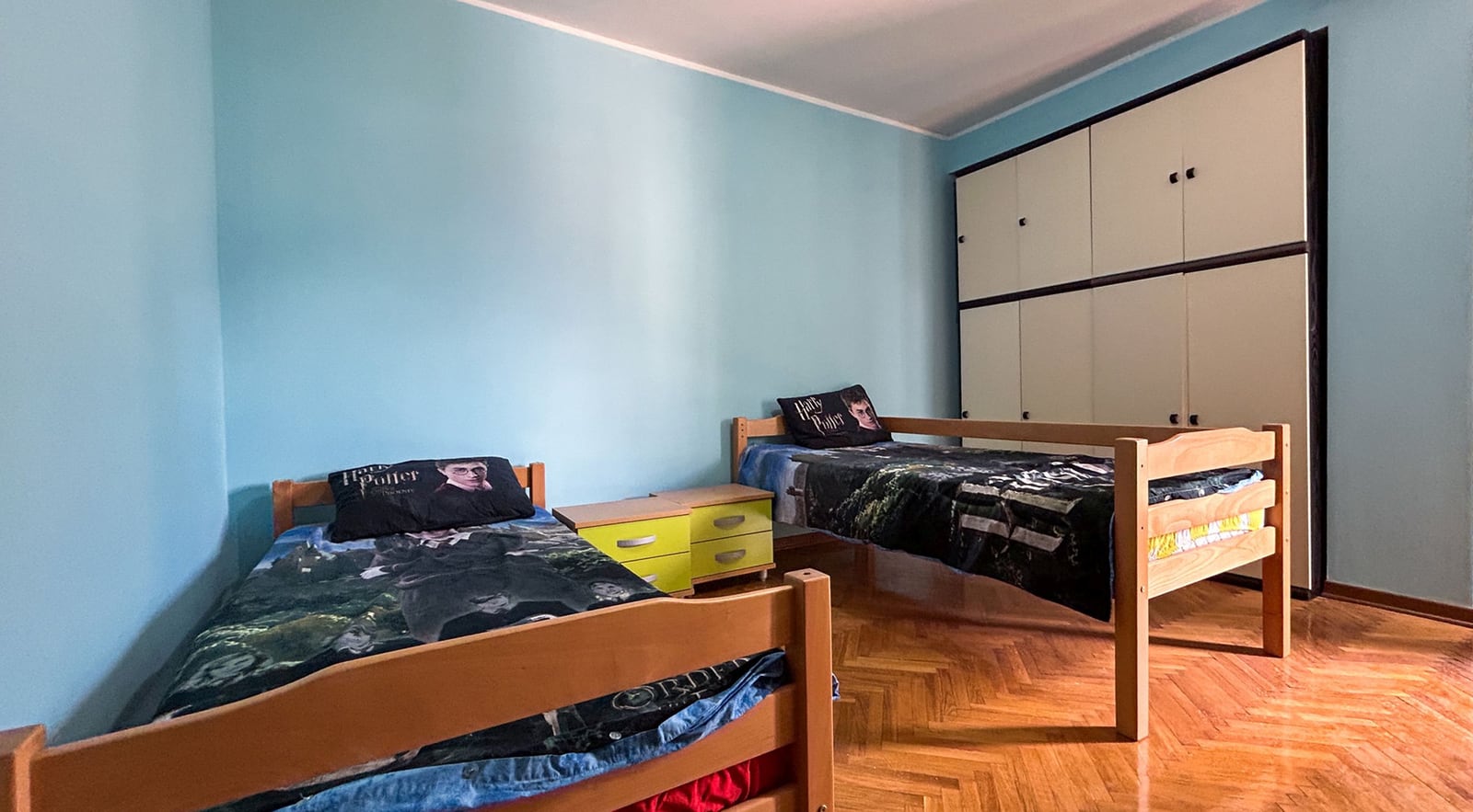 Kinderzimmer mit zwei Betten und Einbauschrank in einer Villa in Dobrota, Montenegro. Parkettboden, blaue Wände.