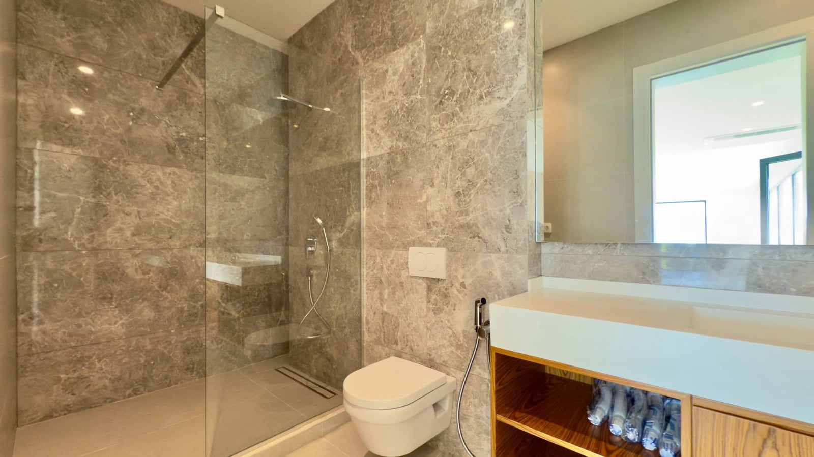 Modernes Badezimmer mit grauer Marmorverkleidung in einer Villa, Krašići, Montenegro: Dusche und hängende Sanitäranlagen.