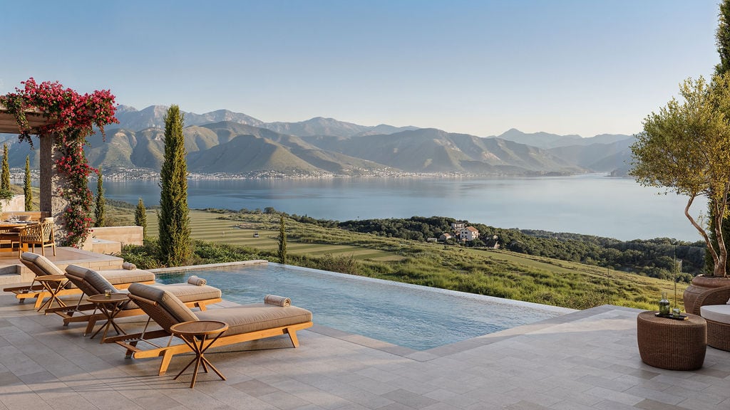 Infinity pool with a view of the bay and mountains in the elite Luštica complex, Montenegro, with a terrace and sun loungers.