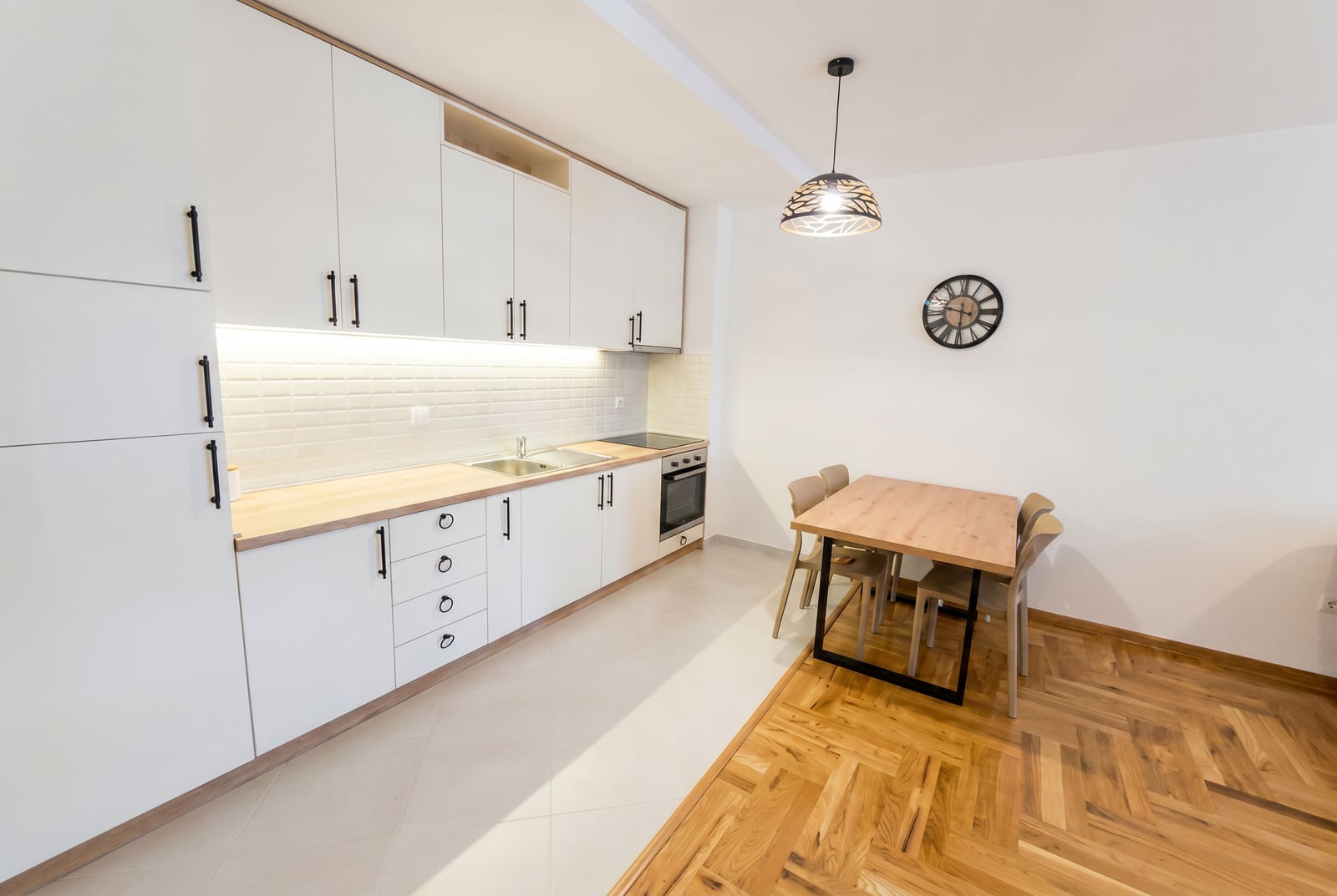 Nowoczesna kuchnia z białymi meblami i jadalnią w apartamencie, Rafailovići, Czarnogóra.