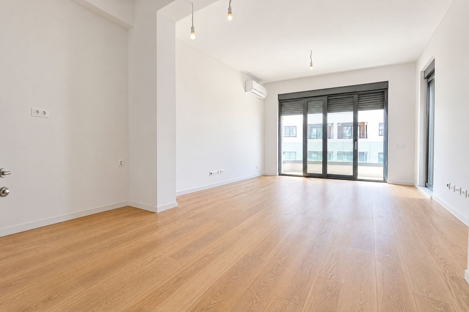 Bright empty living room with a panoramic window and parquet flooring in an apartment in Becici, Montenegro